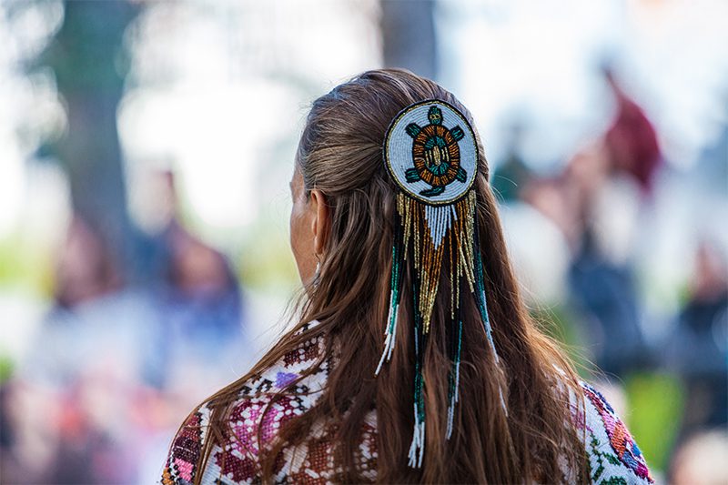 Woman is wearing a large turtle beaded hair pin.